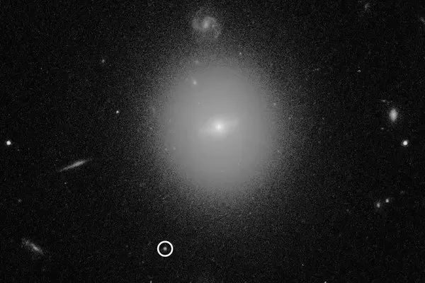 A Hubble Space Telescope image showing the location of an intermediate-mass black hole, named 3XMM J215022.4-055108, indicated by the white circle.